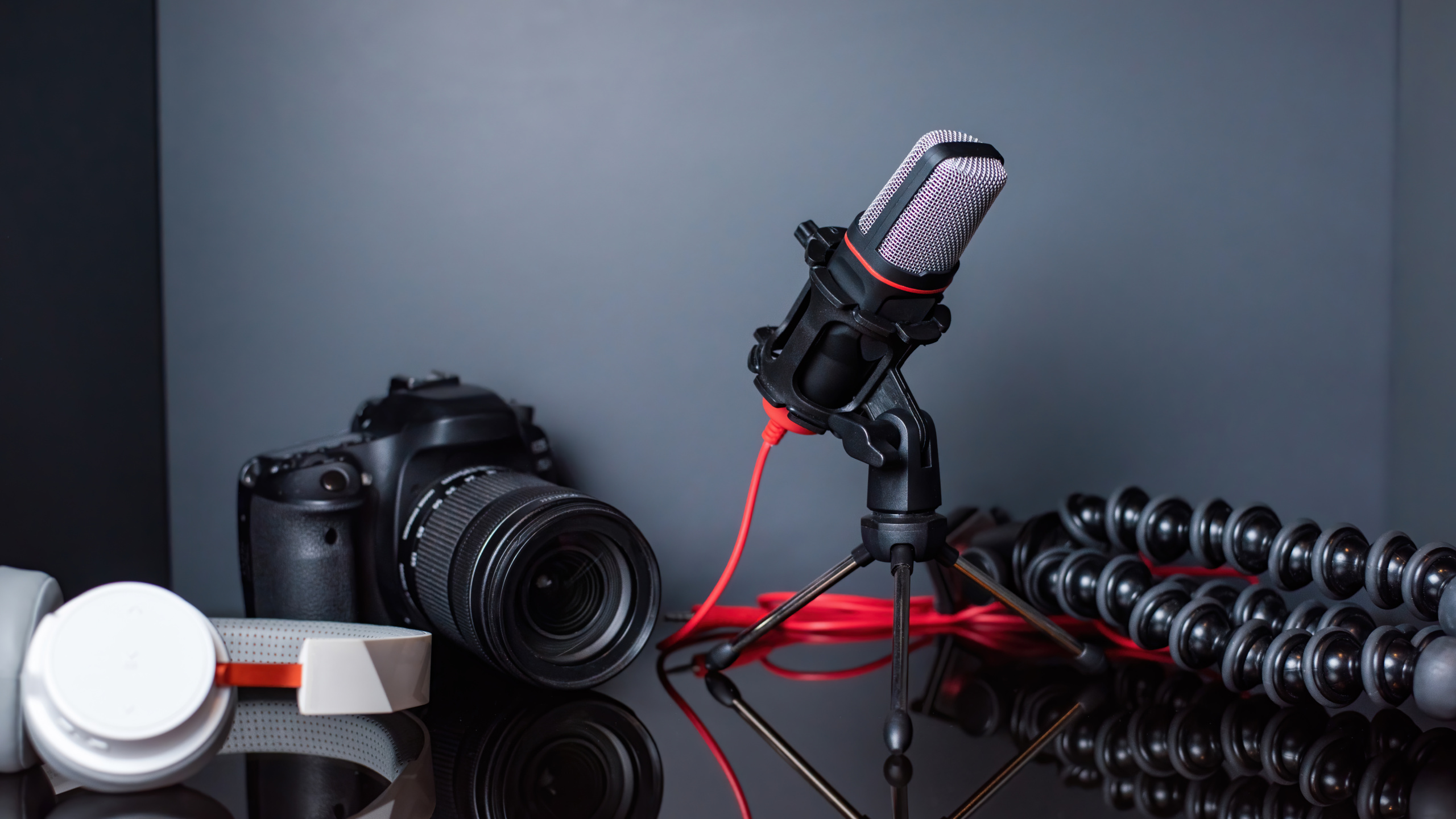 Table with content creator stuff. Camera, microphone, tripod and headphones. Working from home